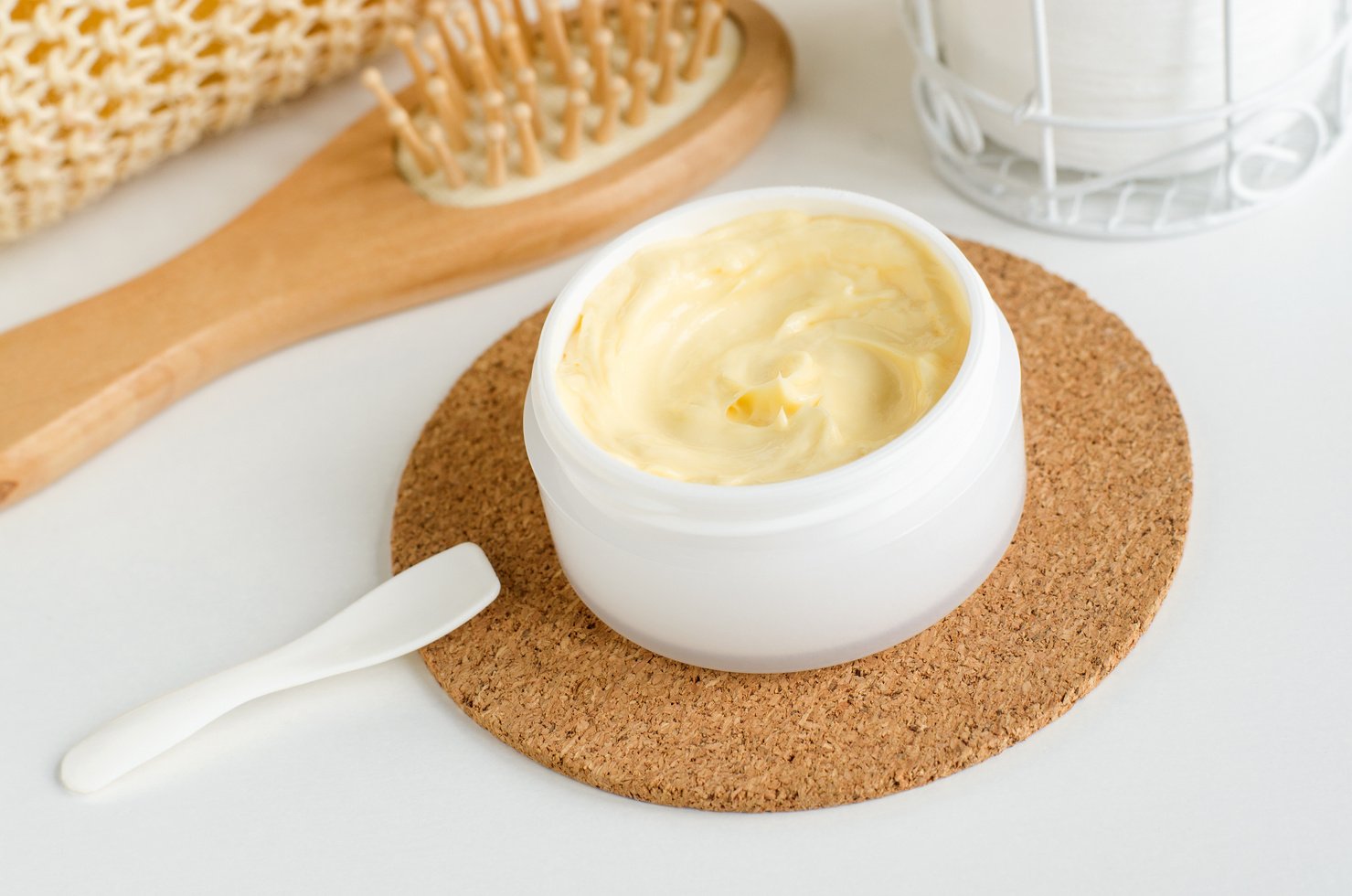 Yellow facial mask (banana face cream, shea butter hair mask, body butter) in the small white jar. Natural skin and hair concept.