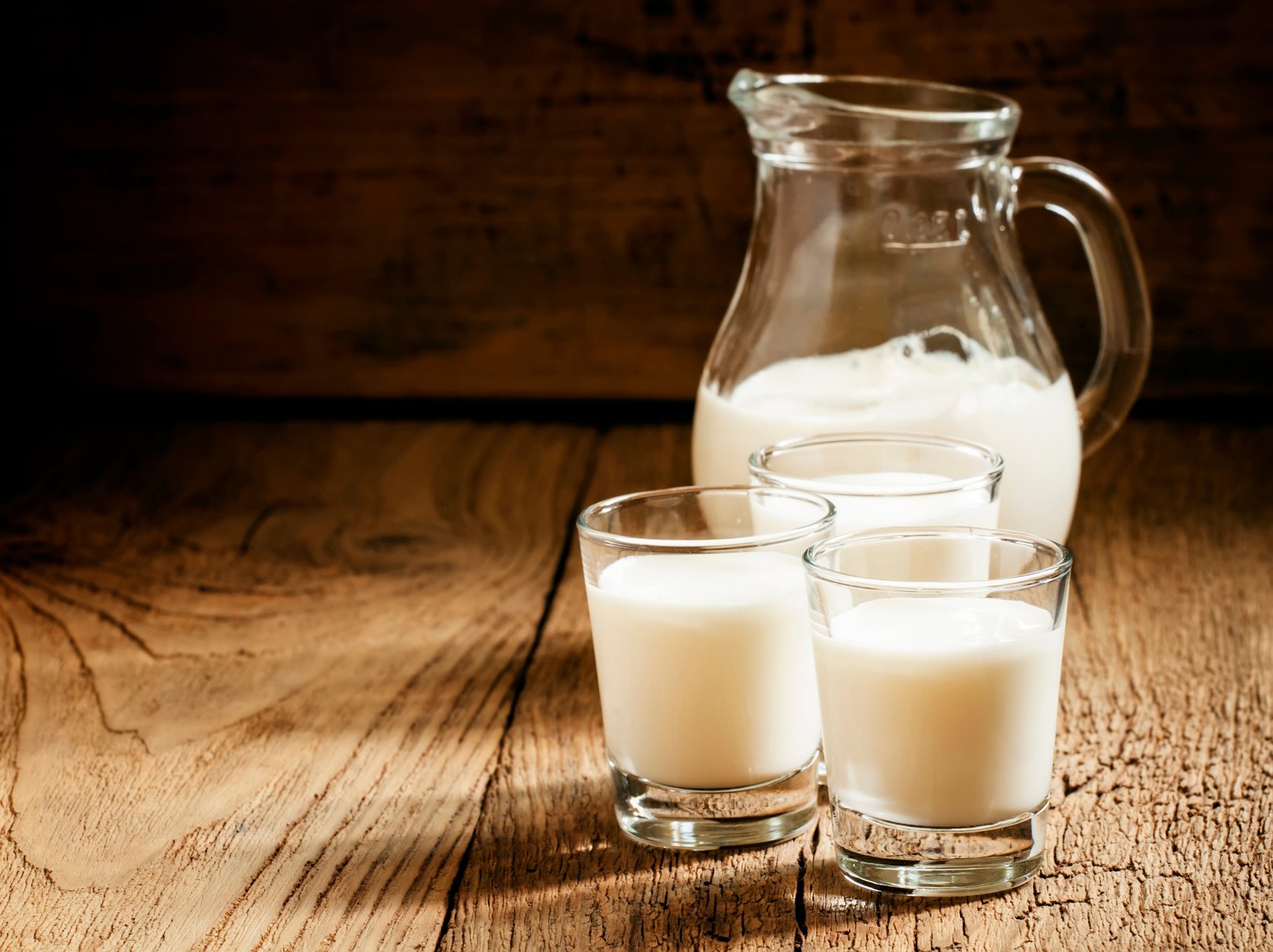 Goat milk in glasses, vintage wooden background